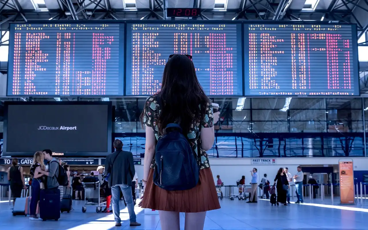 Mulher analisando painel de voos no aeroporto