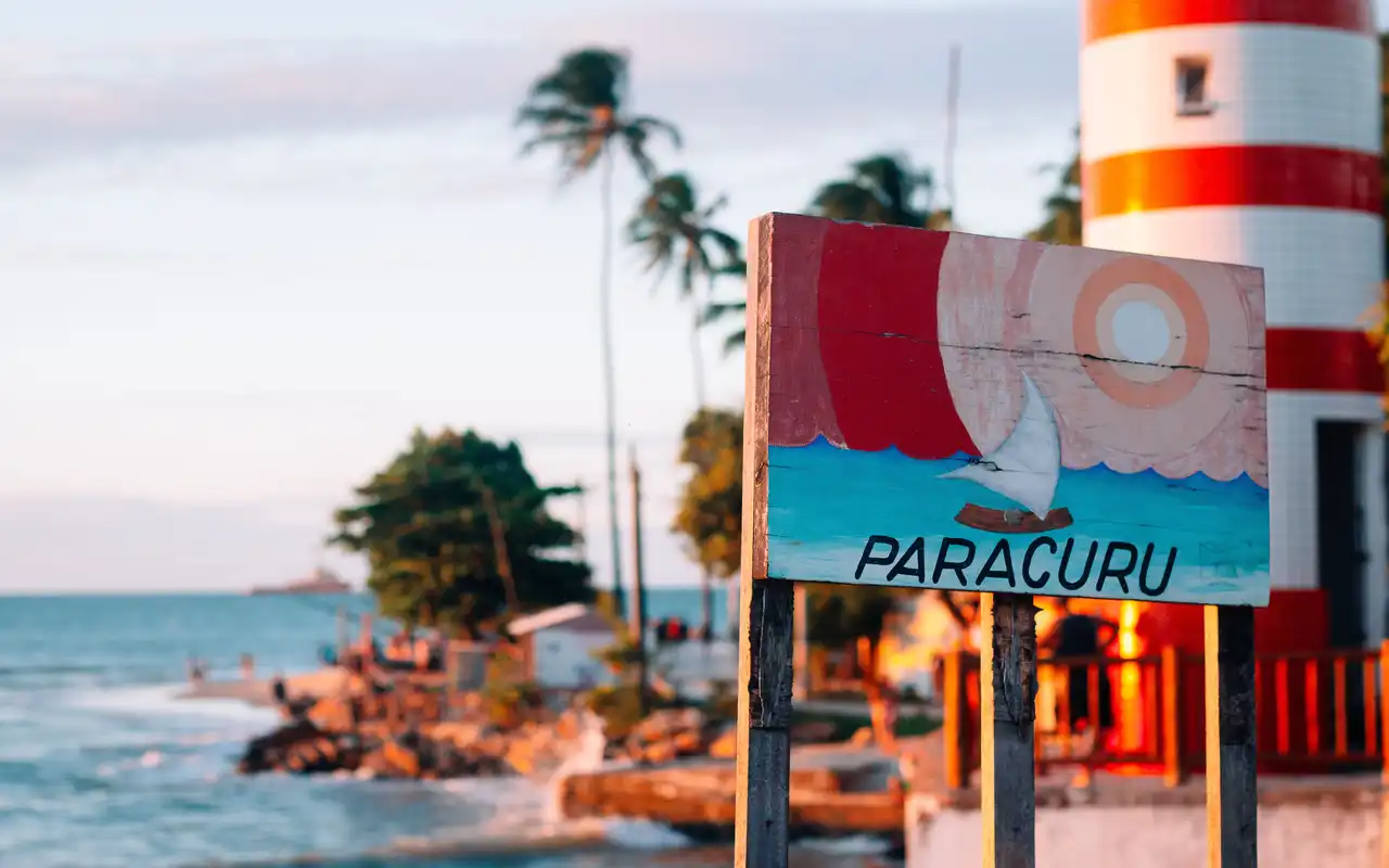 Placa na praia de Paracuru com fundo o famoso farol