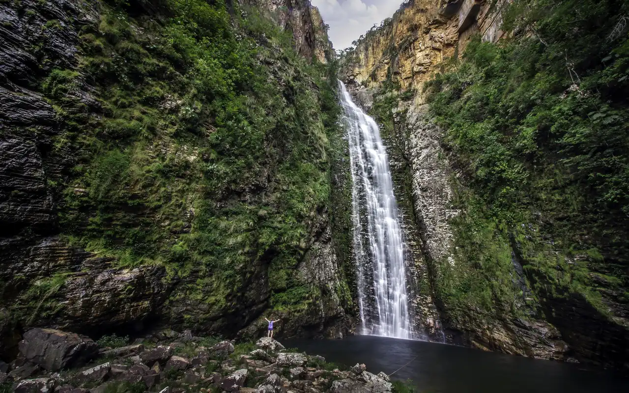 As águas cristalinas e o imponente paredão de mais de 100 metros da Cachoeira do Segredo, um dos cenários mais deslumbrantes da Chapada dos Veadeiros