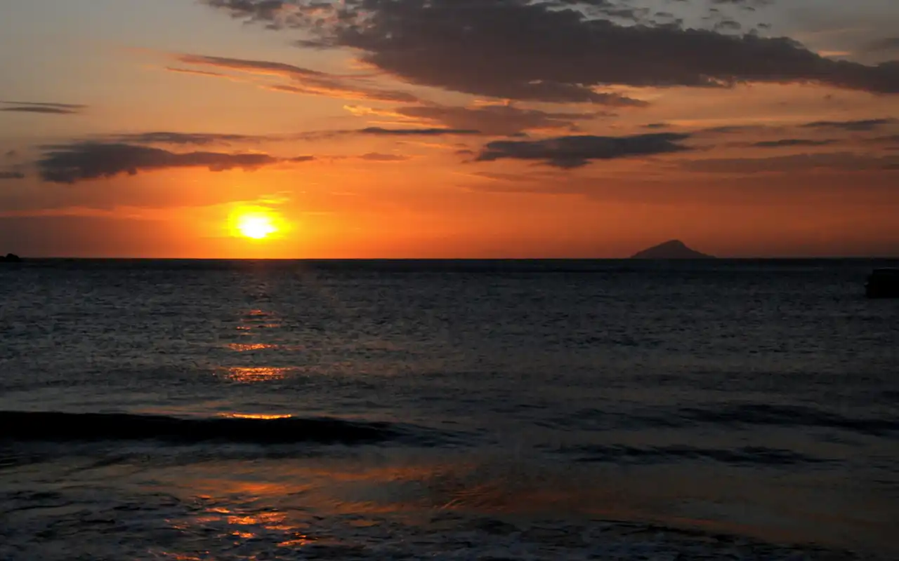 Lindo pôr do sol na Praia de Toque-Toque Pequeno em São Sebastião, SP. Céu colorido refletindo no mar calmo e na areia desta charmosa antiga vila de pescadores.