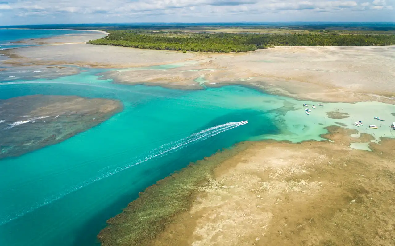 Barcos turísticos atracados nas águas cristalinas das piscinas naturais de Garapuá e Boipeba