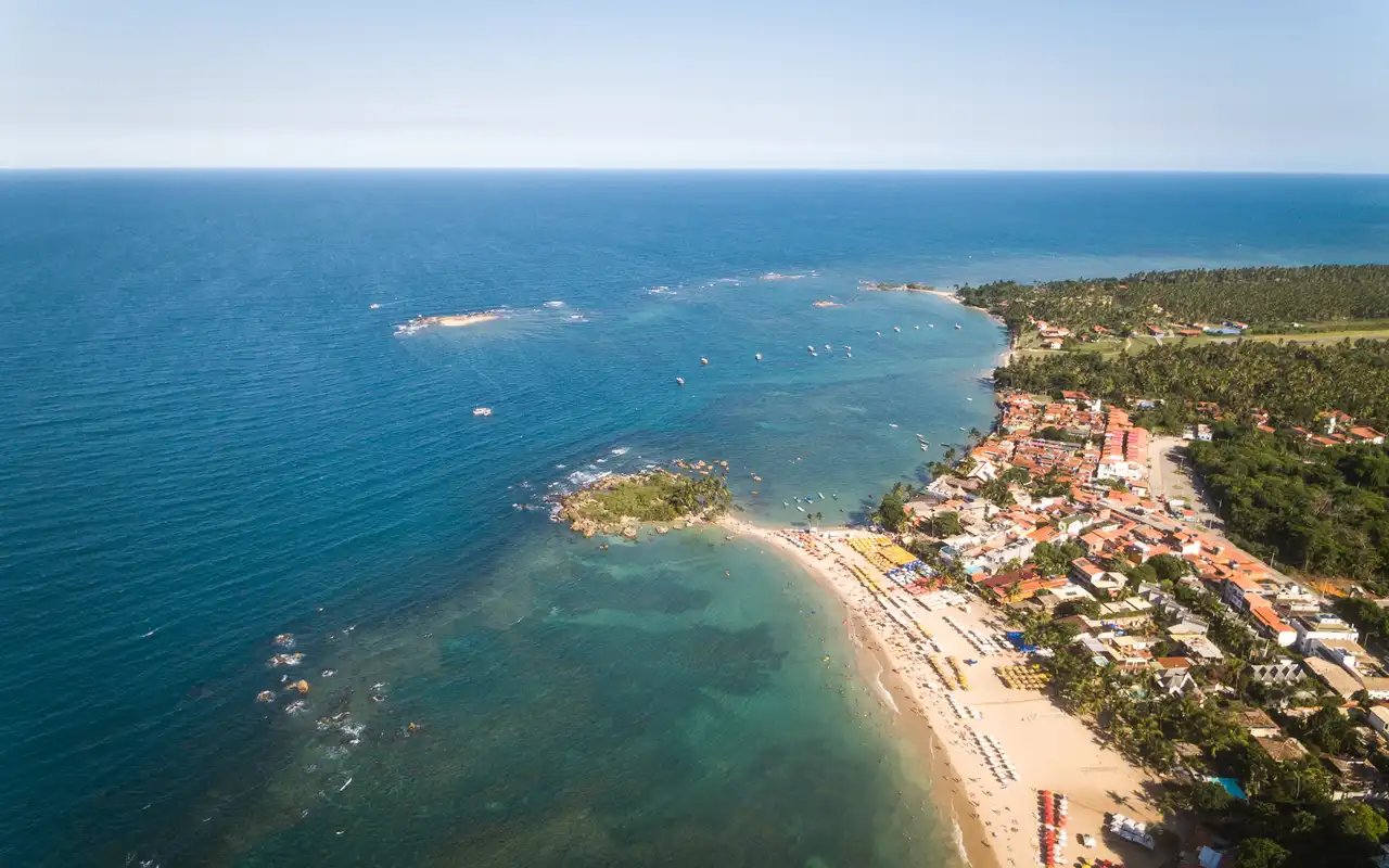 Orla movimentada com barracas e águas calmas na Segunda Praia em Morro de São Paulo